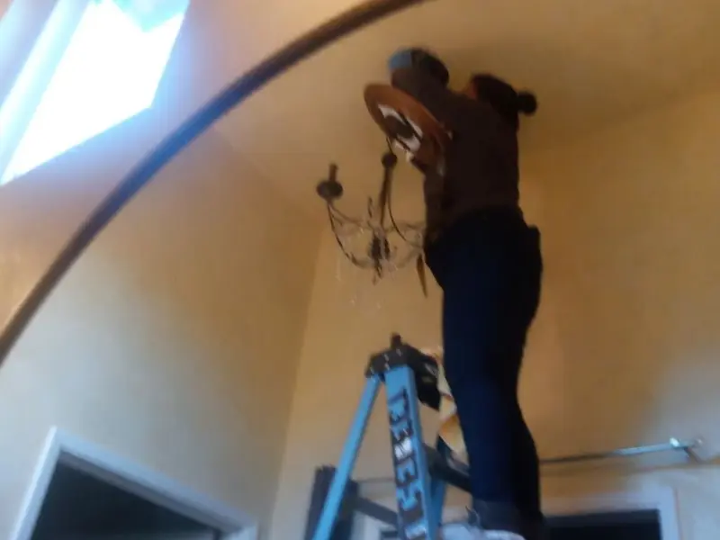 Electrician installing a chandelier in a Yellow Springs residence